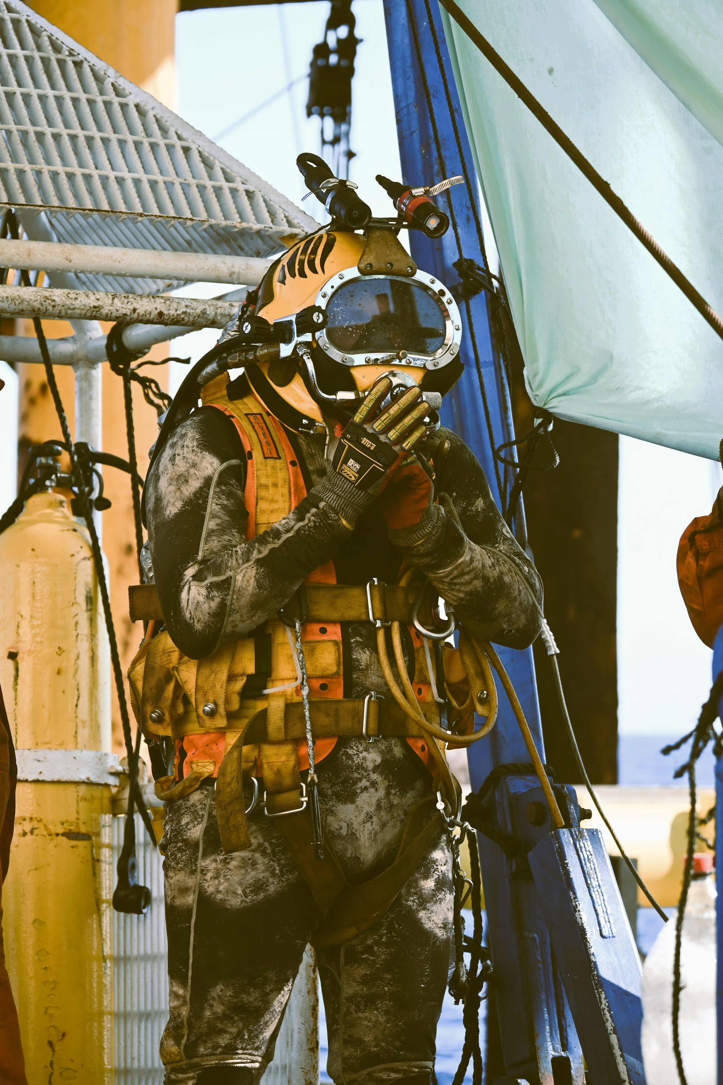 Illustrative stock photograph of a commercial diver in a yellow helmet preparing on deck